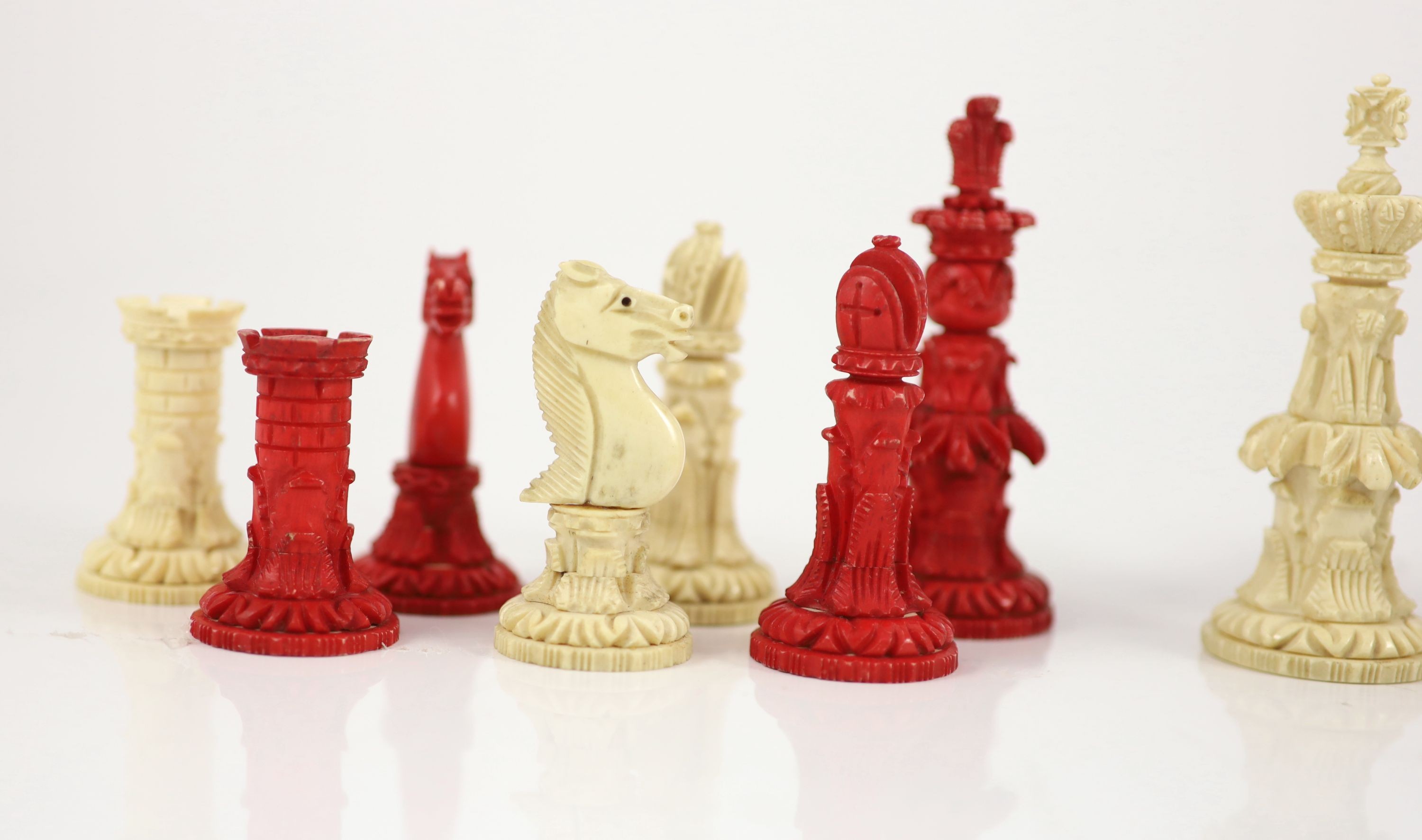 A 19th century Anglo-Indian white and stained bone chess set, with unusual carved palmate decoration, Kings 9.5cm.